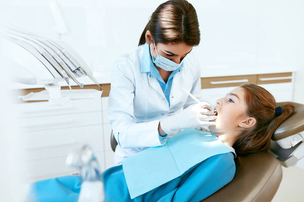 Stomatology. Dentist Working With Girl Teeth In Dental Clinic.