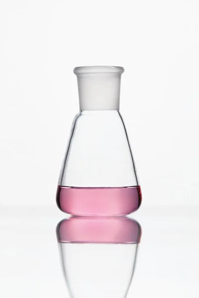 Laboratóriumi üvegeszközök. Üveg fehér alapon Rózsaszín folyadék — Stock Fotó