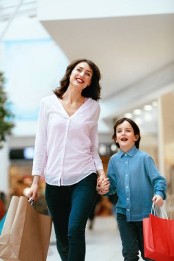 Alışveriş. Genç anne ve çocuk elinde çanta alışveriş merkezinde
