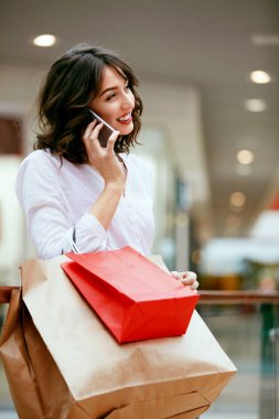 Alışveriş. Gülümseyen kadın telefon alışveriş merkezinde kullanarak