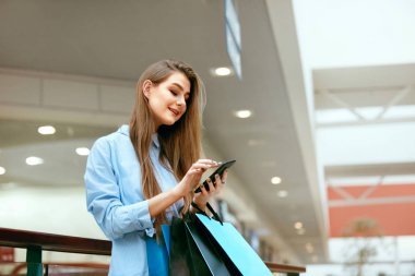 Alışveriş. Gülümseyen kadın telefon alışveriş merkezinde kullanarak