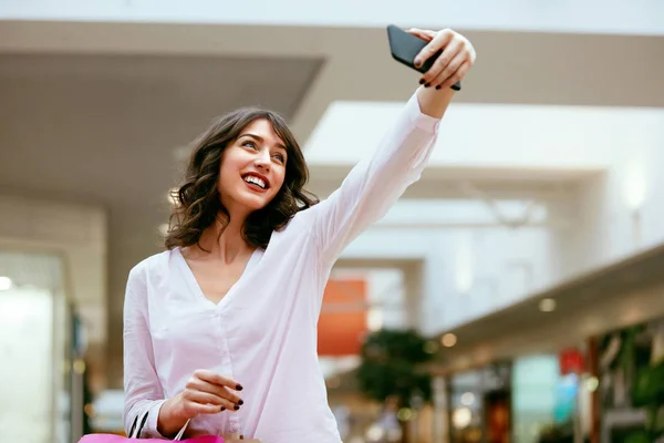 A fare shopping. Donna sorridente che scatta foto nel centro commerciale — Foto Stock