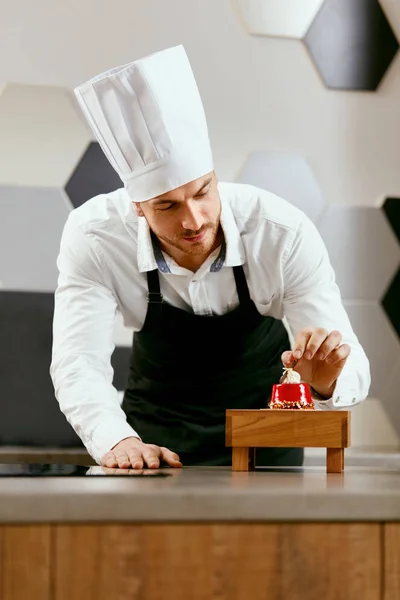 Male Pastry Cook Decorating Dessert In Kitchen