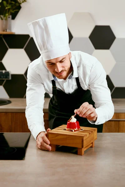 Male Pastry Cook Decorating Dessert In Kitchen