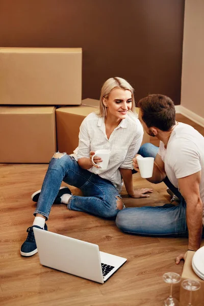 Lyckliga paret i nya hus sitter på golvet — Stockfoto