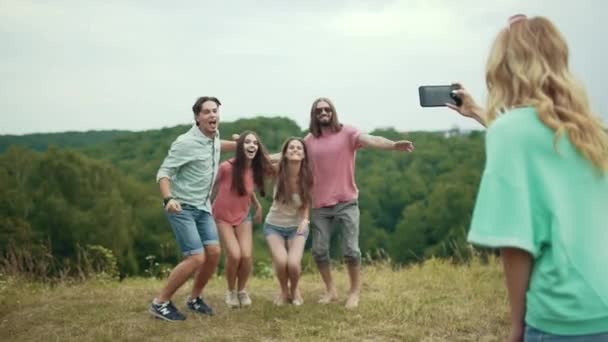 Amigos saltando e se divertindo ao tirar fotos na natureza — Vídeo de Stock