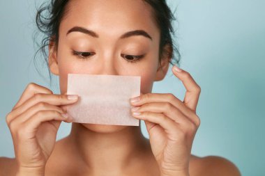 Skin care. Woman holding facial oil blotting paper portrait clipart