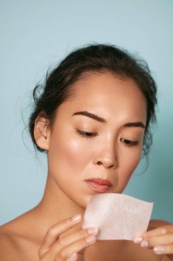 Skin care. Woman holding facial oil blotting paper portrait clipart