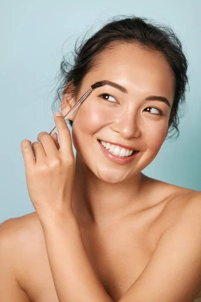 Makeup. Wanita menggosok alis dengan kuas alis menutup potret — Stok Foto