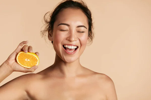 Belleza. Mujer sonriente con la piel radiante de la cara y el retrato naranja —  Fotos de Stock