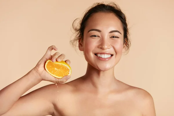 Beleza. Mulher com pele de rosto radiante espremendo retrato laranja — Fotografia de Stock