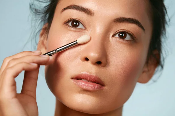 Cantik. Wanita menerapkan makeup pada kulit dengan sikat kosmetik — Stok Foto