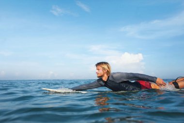 Sörf. Sörf tahtası portresindeki yakışıklı sörfçü. Dalgıç kıyafetli adam okyanusta pratik yapıyor. Aktif Yaşam Tarzı İçin Su Sporu. 