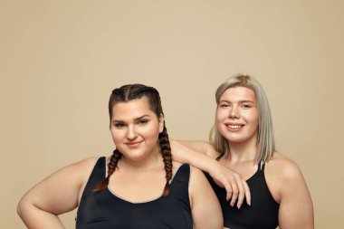 Vücut pozitiftir. Artı Beden Modelleri Portresi. Bej arka planda spor giyimli kadın figürleri. Etkin Yaşam Tarzı İçin Zindelik.