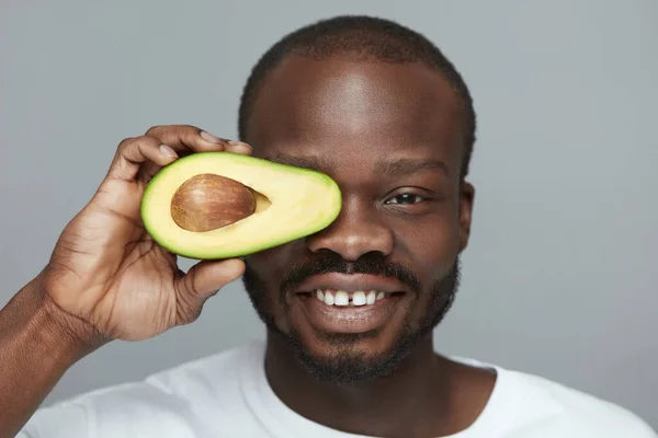 Avocado Skin Care. Male African Model Holds Fresh Fruit Near Face. Facial Treatment With Natural Vitamins.