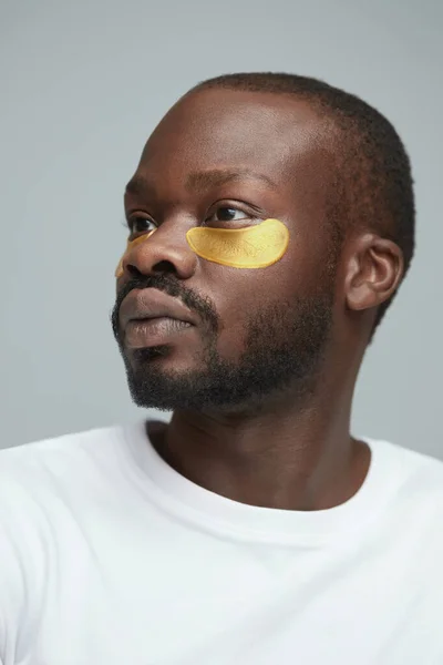 Skin Care. Portrait Of Male Model Applying Yellow Under Eye Patches. Beauty Cosmetic Mask On Face. Facecare Routine. Cosmetology Facial Treatment.