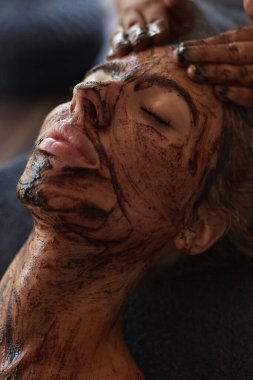 Spa Suratlı Maske. Cilt Bakımı için Güzellik Tedavisi. Güzellik Uzmanı, Kadın Yüzüne Masaj Yapıyor. Doğal Kozmetik Prosedürü Üzerine Gevşek Model.