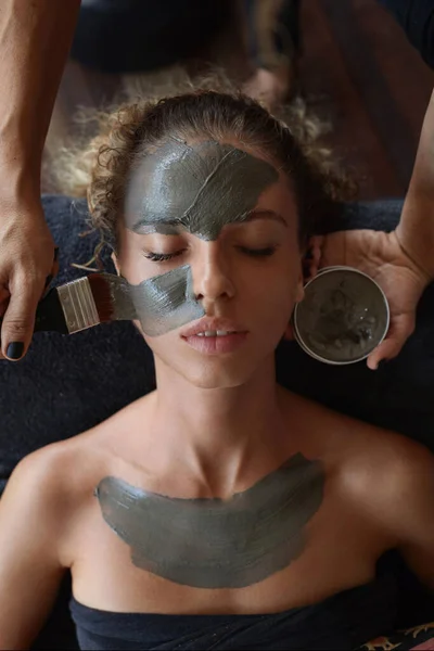 スパフェイスマスク スキンケアのための美容トリートメント 女性の顔に泥を適用する美容師 天然化粧品の手順上のリラックスモデル — ストック写真