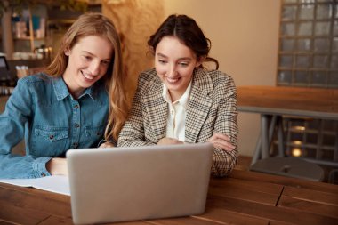 Öğrenciler. Dizüstü bilgisayarla çalışan kızlar. Cafe 'de ders alan güzel genç kadınlar. Gülümseyen Sarışın ve Esmer Ekrana bakıyor ve bir şeyler yazıyor.