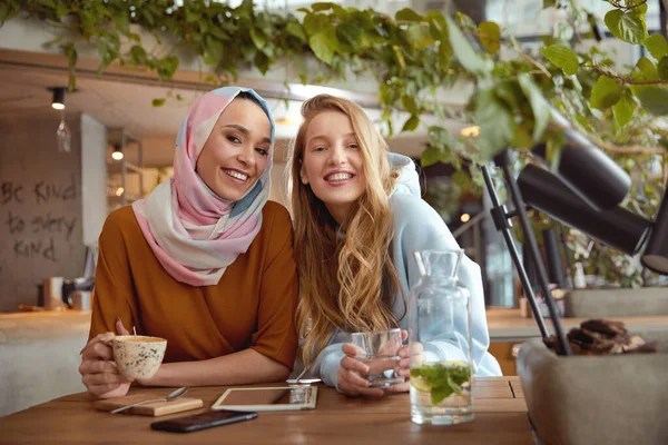 Girls. Beautiful Women Meeting In Cafe. Smiling Friends Drinking Coffee And Looking At Camera. Different Ethnicity Friendship.