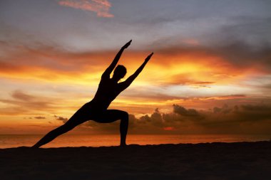 Yoga pozları. Ocean Beach 'te Angle Asana' yı deneyen kadın. Güzel Gün Batımında Parivrtta Parsvakonasana 'da Duran Kadın Silueti. Yaşam Tarzı Egzersizi olarak Yoga.