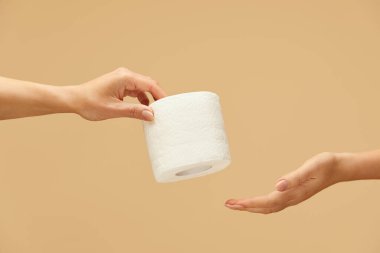 Hijyen. Beyazların arka planında beyaz kadın eli olan tuvalet kağıdı rulosu. Bir kadın diğerine kağıt mendil veriyor. Sağlıklı kalmak için yüksek kaliteli ürünler kullanılıyor.. 