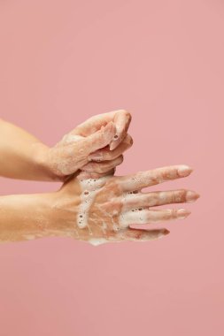 Temizlikçi Eller. Pembe arka planda sabun köpüğüyle kaplı kadın kolları. Enfeksiyonu önlemek için anti bakteriyel ürünler ve kişisel hijyen kullanımı. 