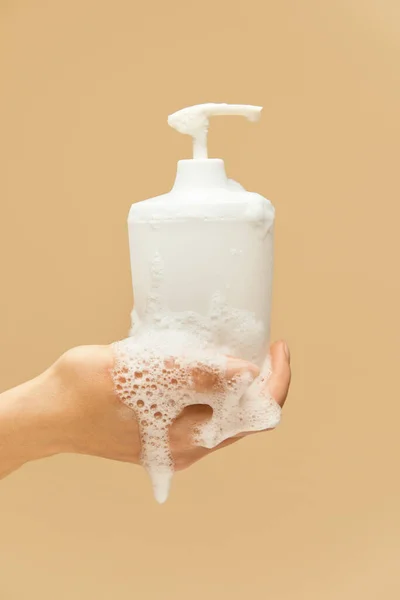 个人卫生设备 在米色背景下 用泡沫保持液体肥皂瓶覆盖手部 洗手预防病毒及保持健康 — 图库照片
