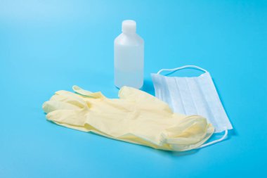 Tek kullanımlık tıbbi maske, antiseptik ve lateks eldiven açık mavi yüzeyde.