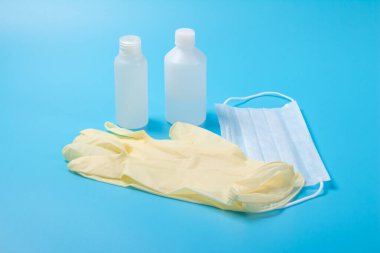 Tek kullanımlık tıbbi maske, antiseptik ve lateks eldiven açık mavi yüzeyde.