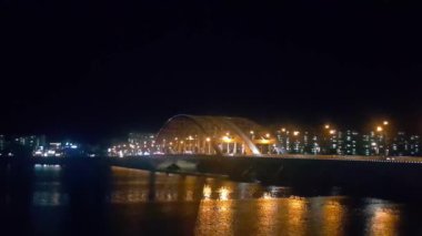 Akşamları deniz suyunun üzerinde renkli ışıklarla güzel bir köprü manzarası..