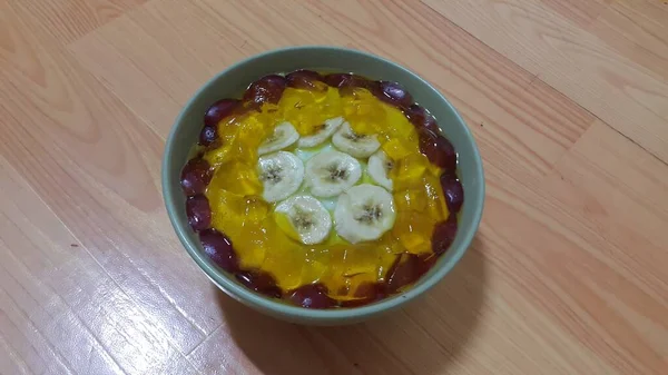 Creamy saboroso creme doce com pedaços de banana na tigela de superfície no chão de madeira — Fotografia de Stock