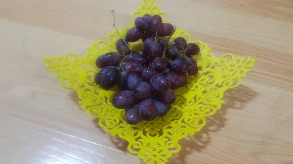 Close up view of bunches of brown grapes served in yellow plastic fruit tray — Stock Photo, Image