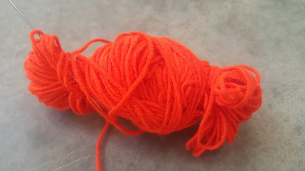 Orange ball of threads wool yarn for knitting on grey floor background — Stock Photo, Image