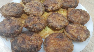 Lezzetli baharatlı kızarmış yuvarlak kebap ahşap zemin üzerinde beyaz seramik plaka servis