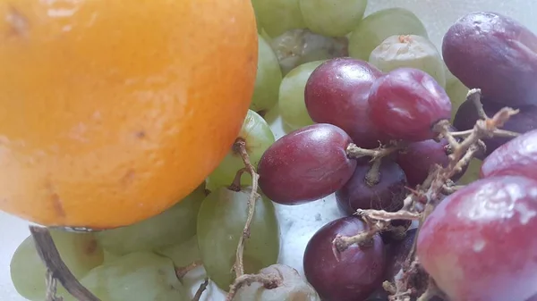 Uma vista de perto de uvas verdes e roxas com laranja . — Fotografia de Stock