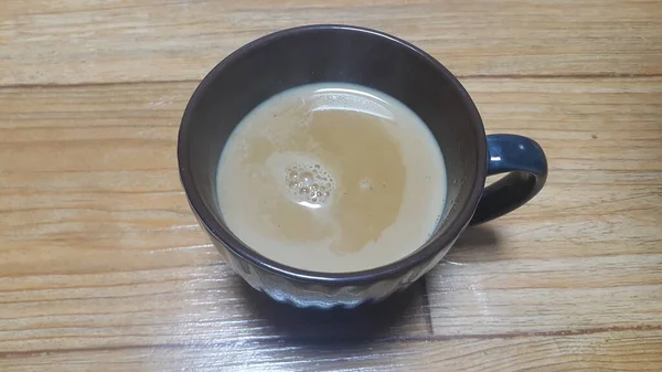 Vista superior de la leche té negro en una taza colocada sobre un piso de madera . —  Fotos de Stock