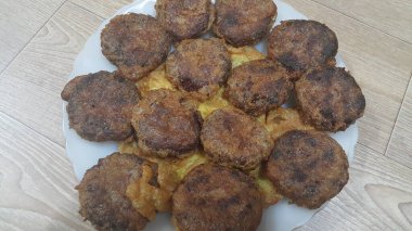 Lezzetli baharatlı kızarmış yuvarlak kebap ahşap zemin üzerinde beyaz seramik plaka servis