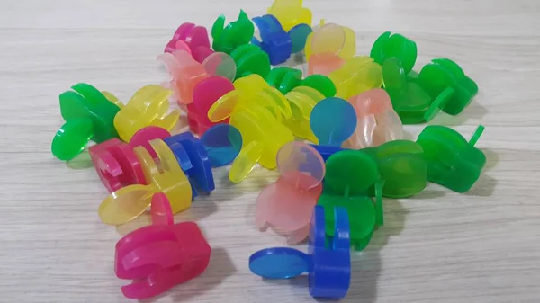 Una gran cantidad de pequeños clips de sujeción de colores colocados en un piso de madera —  Fotos de Stock