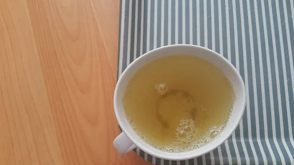 Вид зверху на зелений чай в чашці, поміщеній в лоток над дерев'яною підлогою — стокове фото