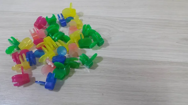 Una gran cantidad de pequeños clips de sujeción de colores colocados en un piso de madera —  Fotos de Stock