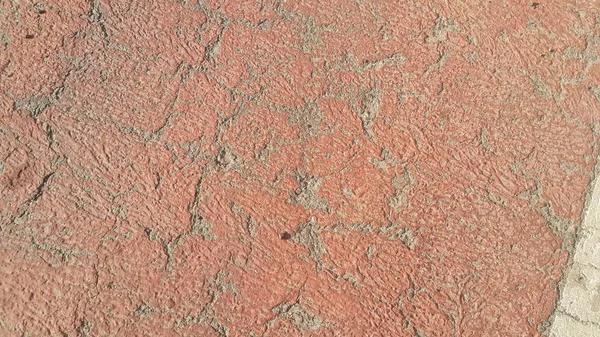 Rot gefärbte beschädigte Straße oder gepflasterter Weg mit Rissen — Stockfoto