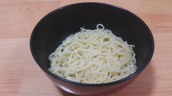 Aproape de vedere de tăiței rotunde sau paste de spaghete într-un castron peste podea de lemn — Fotografie, imagine de stoc