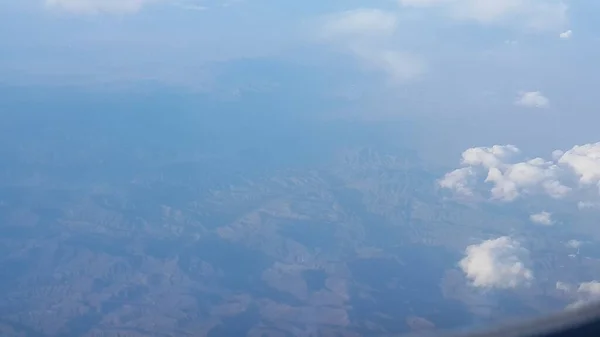 Vista aérea desde la ventana del avión de hermosas nubes y cielo azul — Foto de Stock