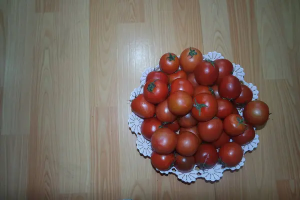 Vue rapprochée de tomates rouges dans un panier blanc sur un plancher de bois au marché — Photo