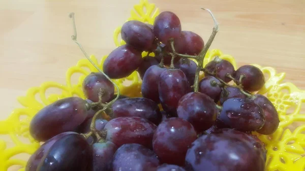 Vista de cerca de racimos de uvas marrones servidos en bandeja de fruta de plástico amarillo — Foto de Stock