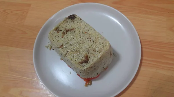 Крупный план замороженного белого рисового пирога в белой тарелке над деревянным полом — стоковое фото