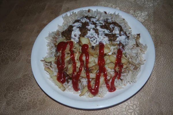 Heerlijk traditioneel gerecht van rijst, aardappelfriet en granen met rode ketchup. — Stockfoto