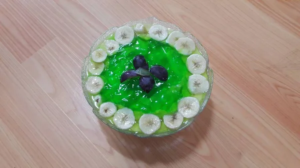 표면에 겹쳐진 바나나 슬라이스를 곁들인 크리미한 맛있는 달콤한 녹색 젤리 — 스톡 사진