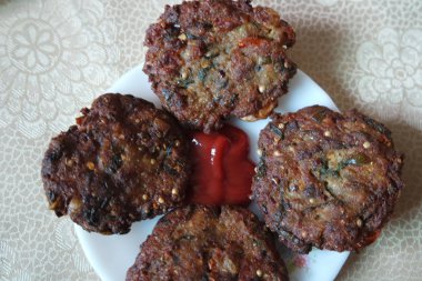 Kırmızı soslu beyaz seramik tabakta servis edilen leziz kızarmış yuvarlak kebap..